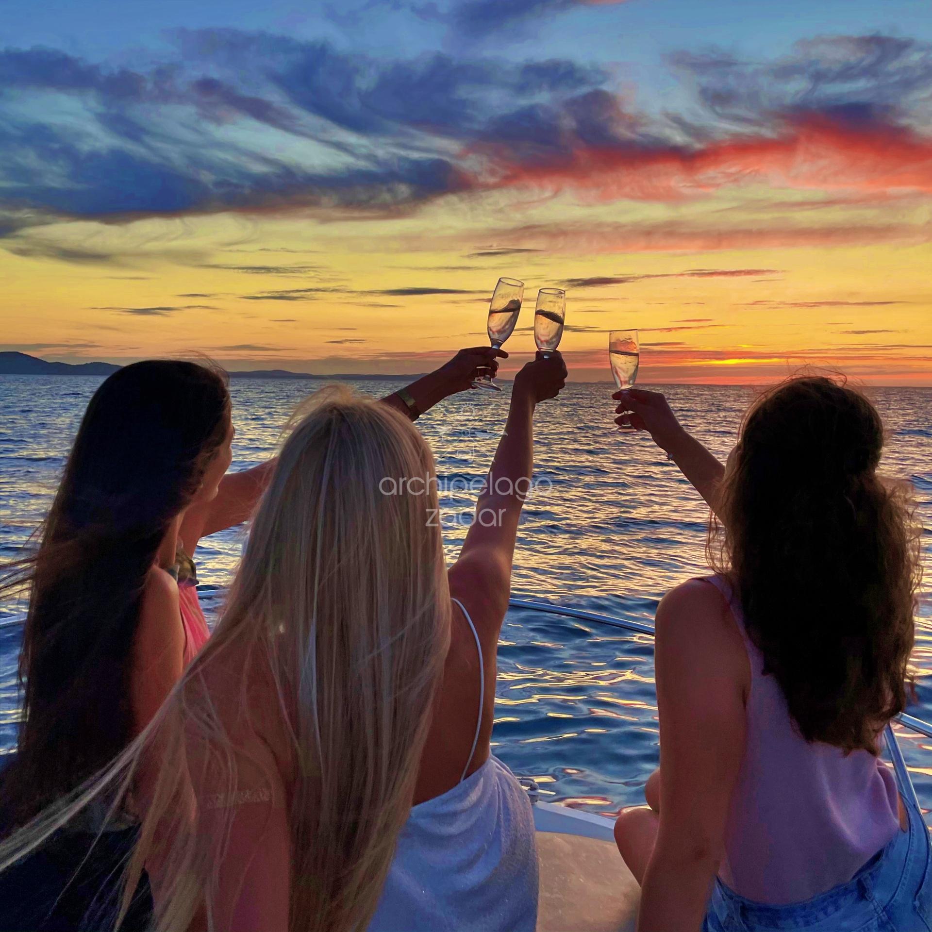 girls toasting on a bnoat in sunset