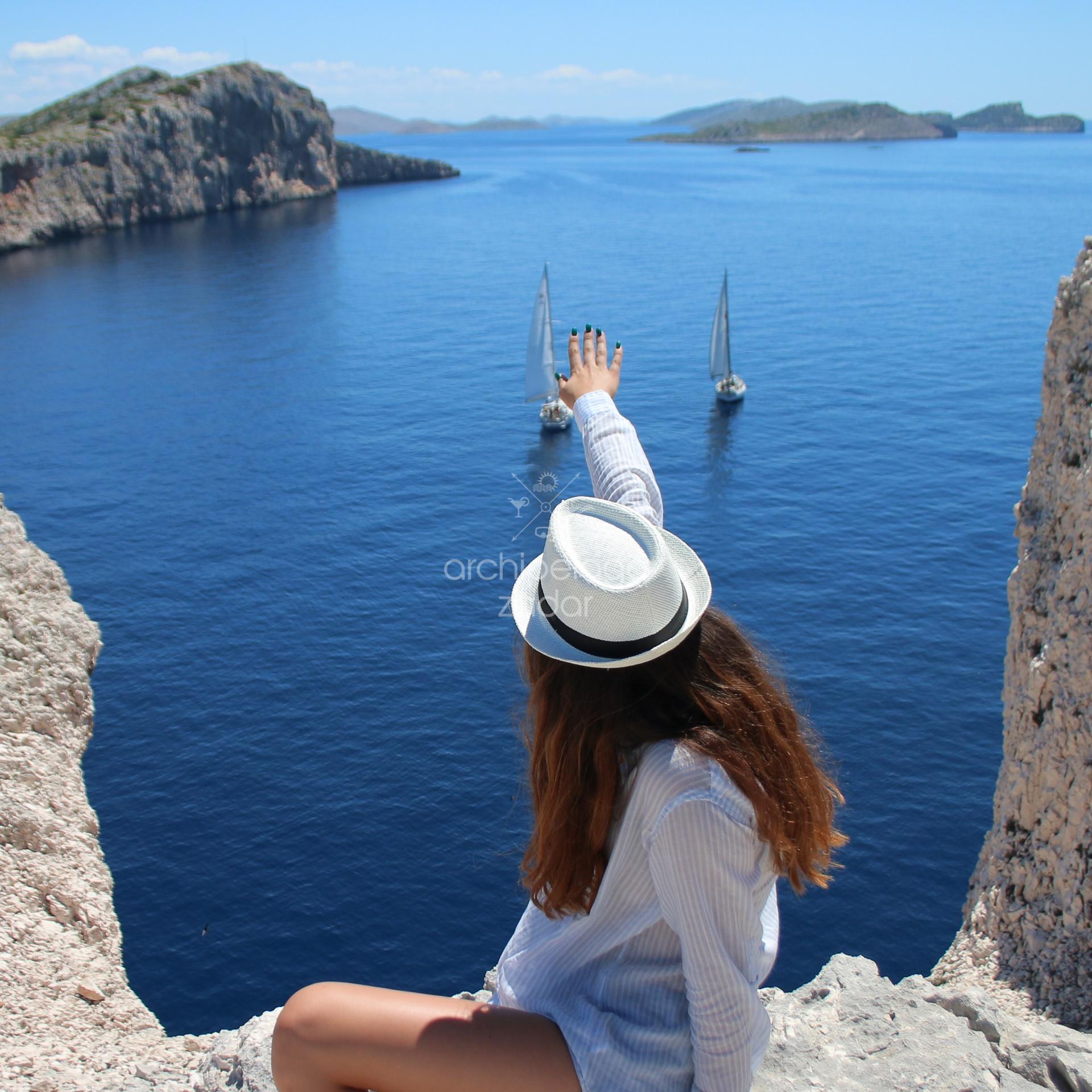 Girl in a hat on a cliff enjoying view on the sea and cliffs