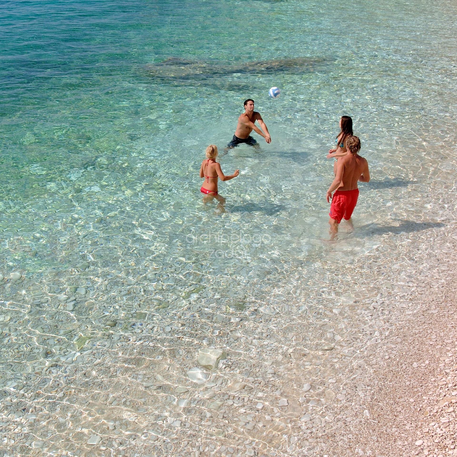 people playing beach volleyball in sandy lagoon