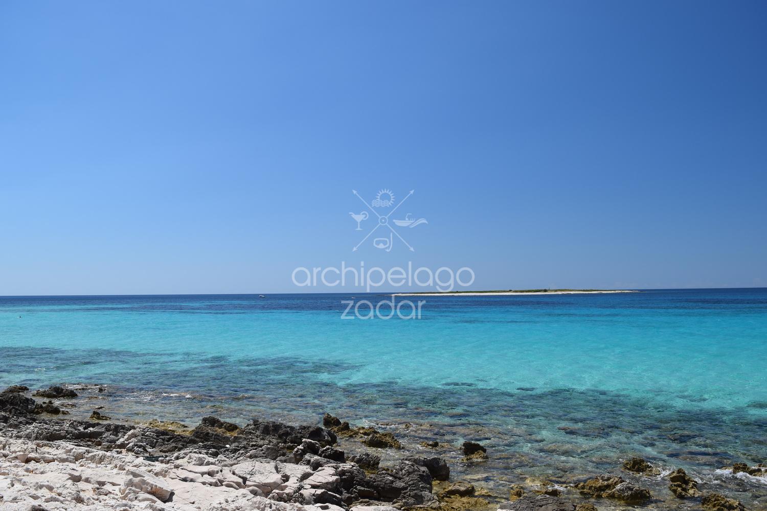 A blue lagoon near the shore with white rocks 
